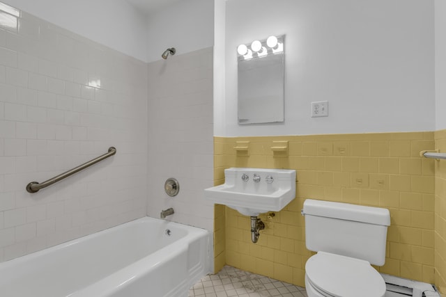 full bathroom with baseboard heating, tiled shower / bath combo, tile patterned floors, tile walls, and toilet