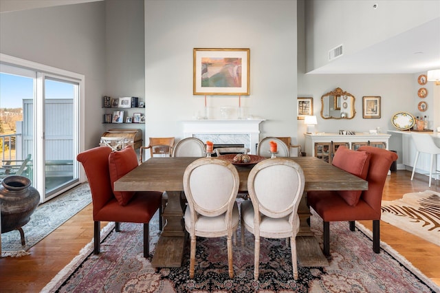 dining room with hardwood / wood-style flooring, high vaulted ceiling, and a high end fireplace