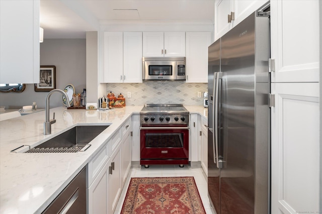 kitchen featuring light stone countertops, white cabinets, appliances with stainless steel finishes, sink, and light tile patterned floors