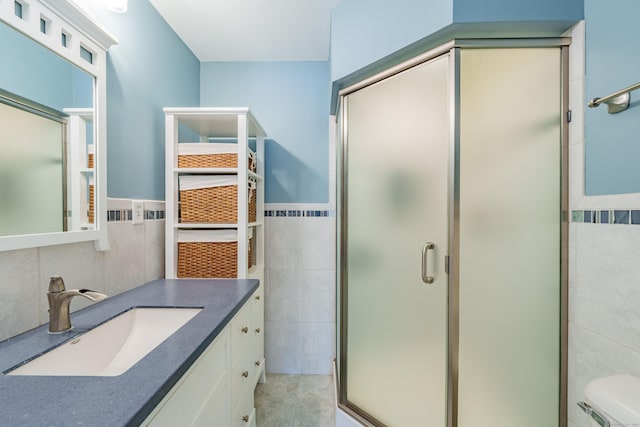 bathroom featuring vanity, toilet, a shower with door, and tile walls