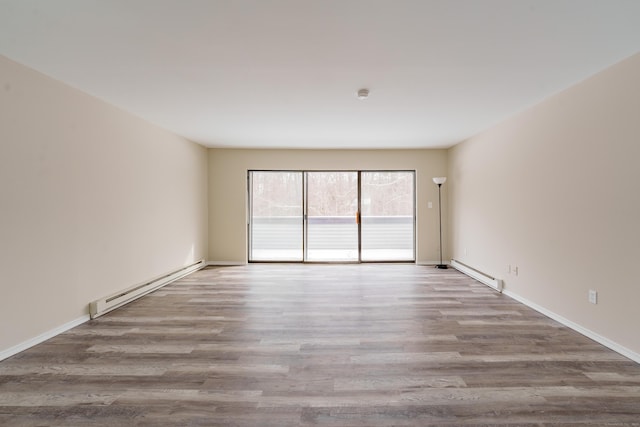 empty room featuring baseboard heating and light hardwood / wood-style floors