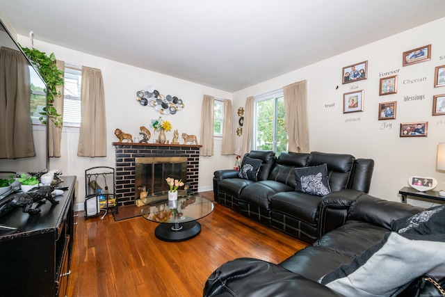 living room with dark hardwood / wood-style flooring, a brick fireplace, and plenty of natural light