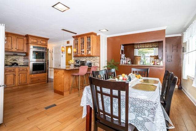 dining space featuring light hardwood / wood-style flooring and crown molding