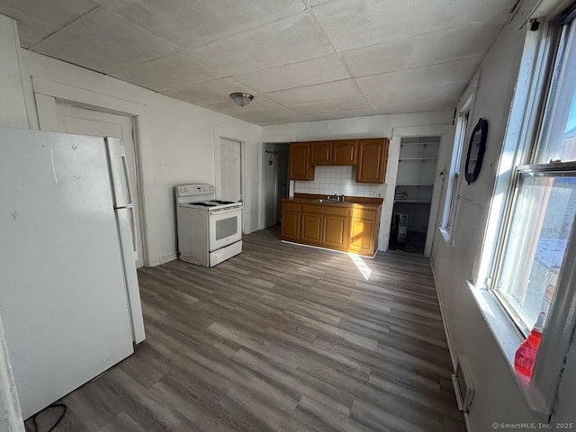 kitchen featuring decorative backsplash, sink, white appliances, and hardwood / wood-style floors