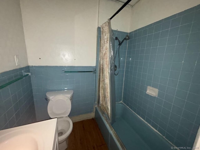 bathroom featuring toilet, tiled shower / bath combo, hardwood / wood-style flooring, and tile walls