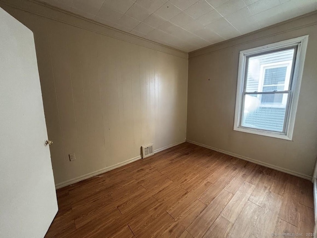 unfurnished room with crown molding and wood-type flooring