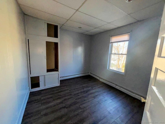 spare room with a paneled ceiling and dark hardwood / wood-style floors