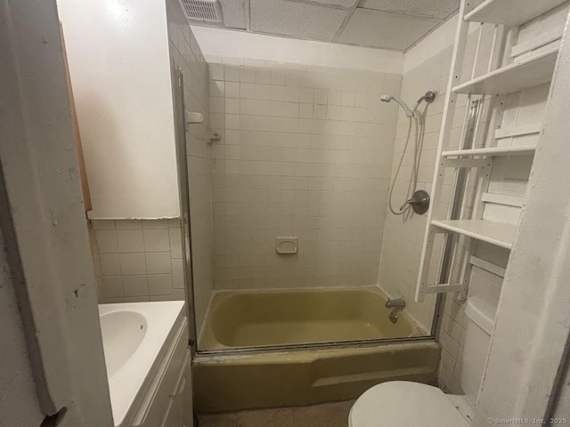 full bathroom featuring toilet, tiled shower / bath, a drop ceiling, and vanity