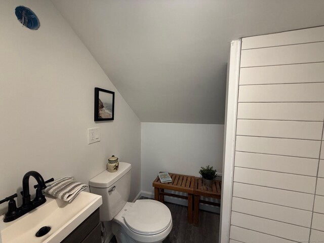 bathroom featuring vaulted ceiling, toilet, wood finished floors, and a sink