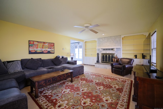 living room with built in shelves, ceiling fan, and a fireplace