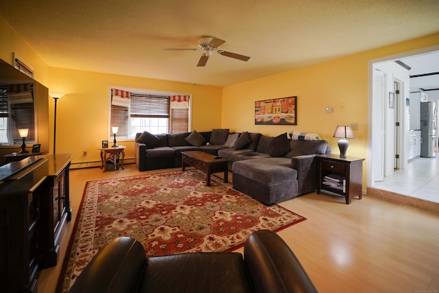 living room with baseboard heating, light hardwood / wood-style flooring, and ceiling fan