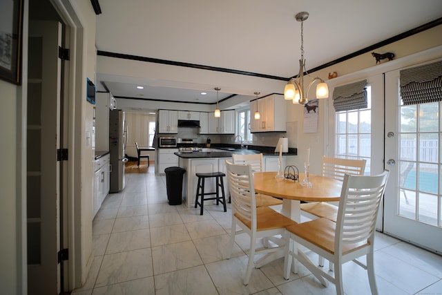 dining room featuring french doors, an inviting chandelier, ornamental molding, and sink