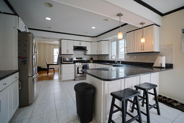 kitchen with kitchen peninsula, sink, white cabinets, and appliances with stainless steel finishes