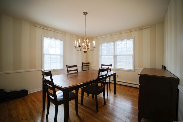 dining area featuring hardwood / wood-style flooring, an inviting chandelier, and a baseboard heating unit