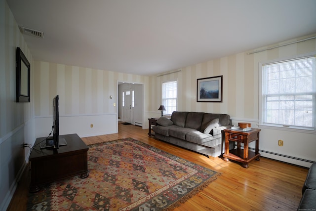 living room with hardwood / wood-style floors, a wealth of natural light, and a baseboard heating unit