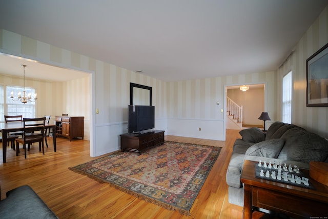 living room with a wealth of natural light, light hardwood / wood-style flooring, and a notable chandelier