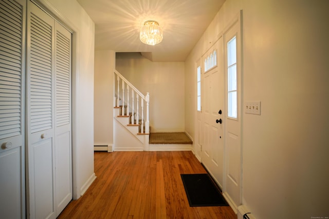 foyer featuring hardwood / wood-style flooring, baseboard heating, and a chandelier