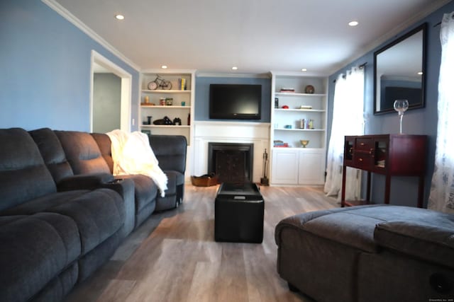 living room with built in shelves, crown molding, and hardwood / wood-style floors