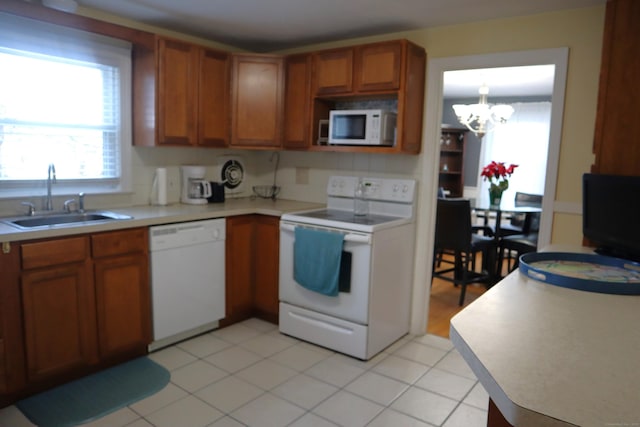 kitchen featuring white appliances, sink, hanging light fixtures, light tile patterned floors, and a chandelier