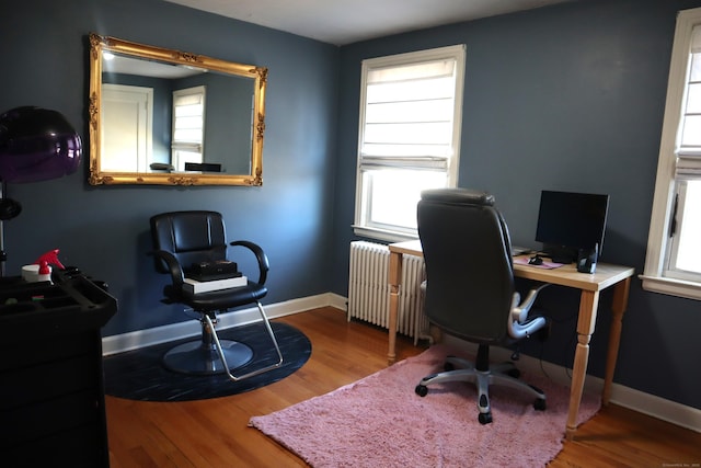 home office with wood-type flooring, plenty of natural light, and radiator