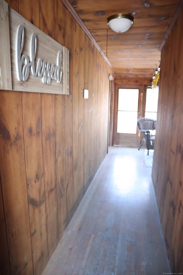 corridor with wood walls, wood ceiling, and light hardwood / wood-style flooring