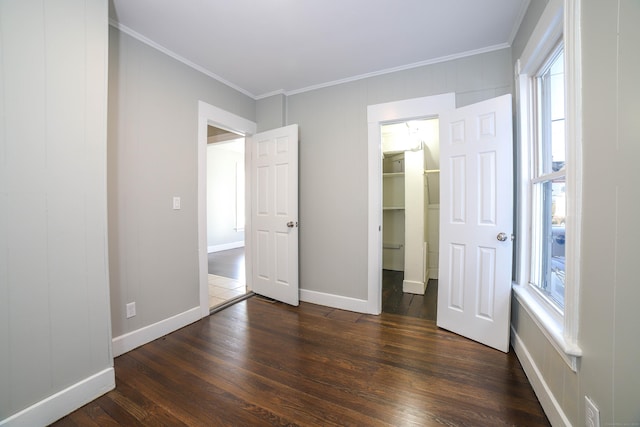 unfurnished bedroom featuring dark hardwood / wood-style floors, ornamental molding, and a spacious closet