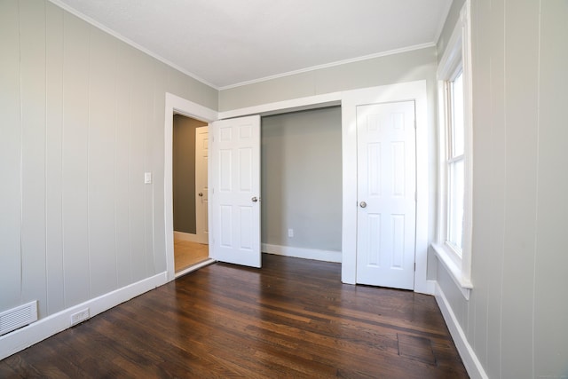 unfurnished bedroom featuring ornamental molding, dark hardwood / wood-style floors, a closet, and multiple windows