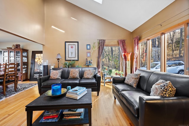 living room with high vaulted ceiling and light wood-type flooring