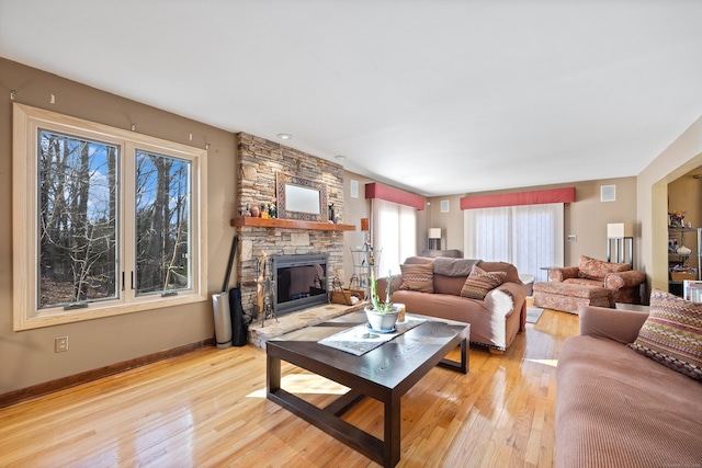 living room featuring light wood-type flooring and a stone fireplace