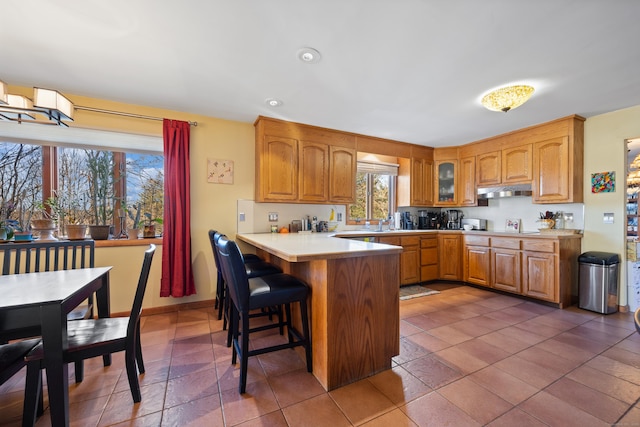 kitchen with a kitchen bar, kitchen peninsula, and dark tile patterned floors