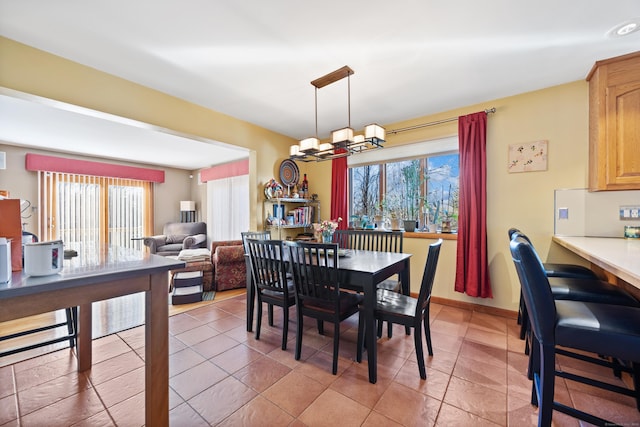 tiled dining area with a healthy amount of sunlight and a chandelier