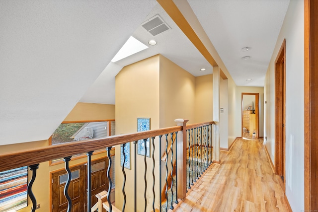 corridor featuring a skylight and light hardwood / wood-style flooring