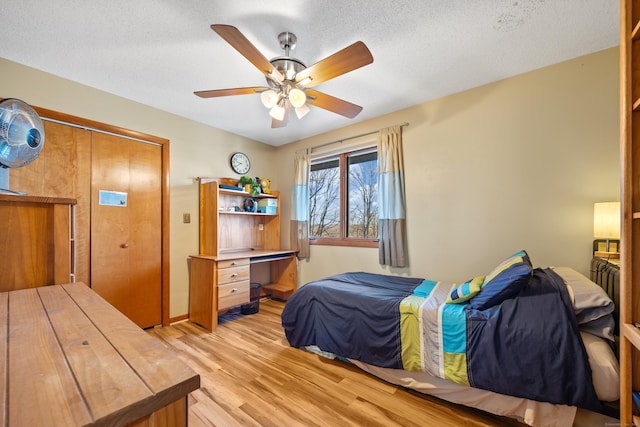 bedroom featuring ceiling fan, a closet, light wood-type flooring, and a textured ceiling