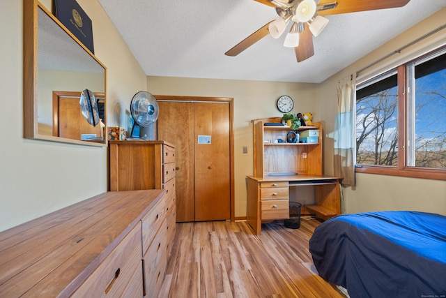 bedroom with ceiling fan, light hardwood / wood-style floors, a textured ceiling, and a closet