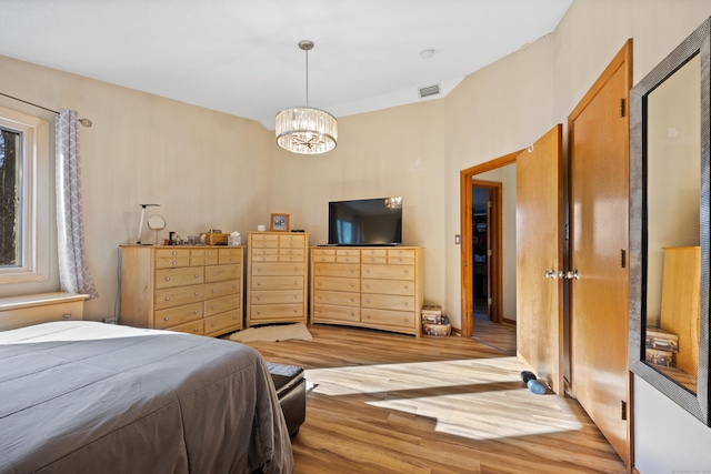 bedroom with a chandelier and light hardwood / wood-style floors