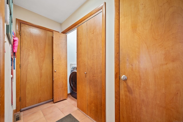 hallway featuring washer / clothes dryer and light tile patterned floors