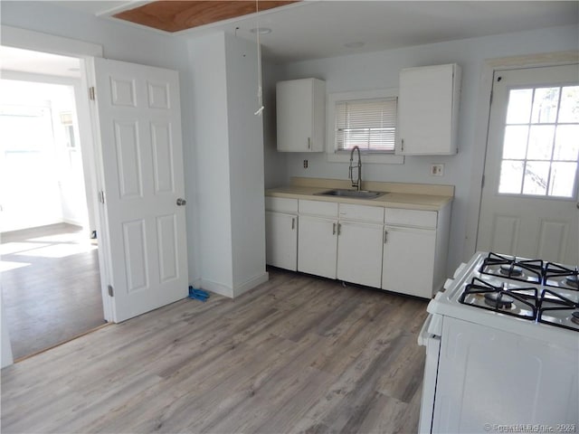 kitchen featuring sink, white gas range oven, white cabinets, and light wood-type flooring