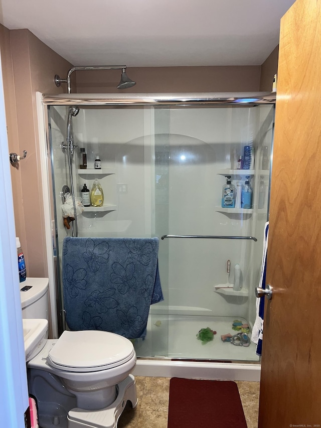 bathroom with a shower with shower door and toilet