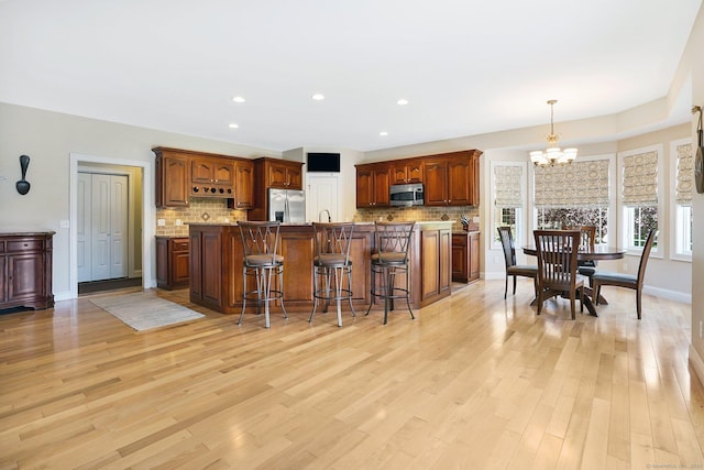 kitchen with a kitchen island with sink, a chandelier, a breakfast bar, and stainless steel appliances