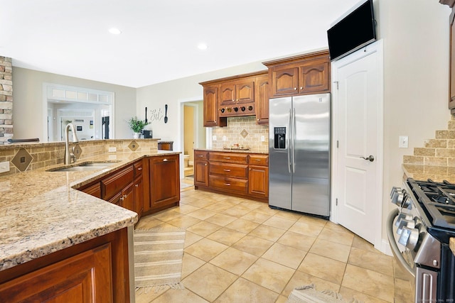 kitchen with light stone countertops, sink, stainless steel appliances, backsplash, and light tile patterned floors