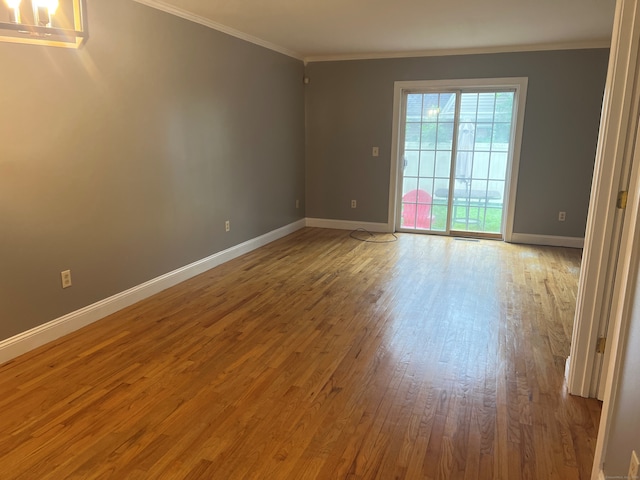 spare room with hardwood / wood-style floors and crown molding