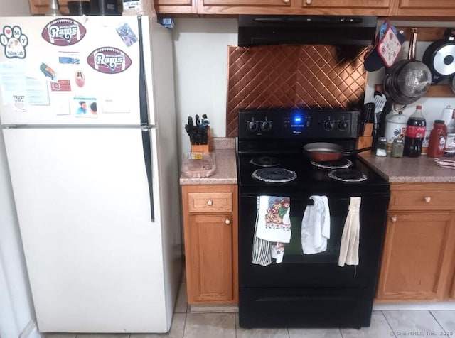 kitchen featuring light tile patterned floors, white refrigerator, extractor fan, and electric range