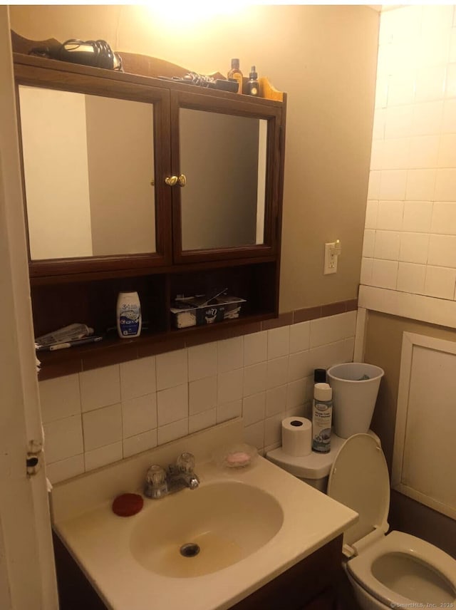 bathroom with vanity, tile walls, and toilet