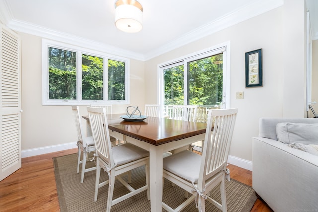 dining space with hardwood / wood-style floors and ornamental molding