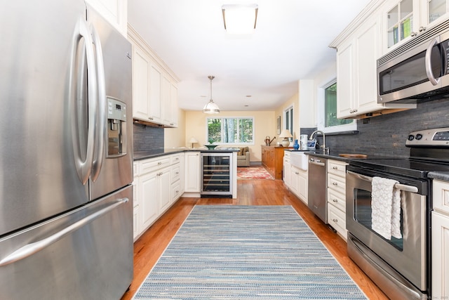 kitchen with backsplash, beverage cooler, hanging light fixtures, and appliances with stainless steel finishes