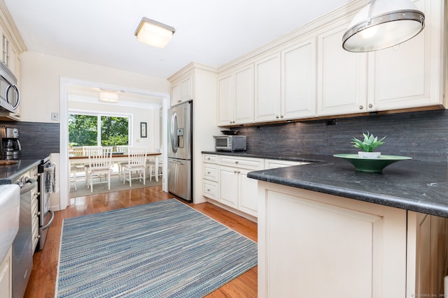 kitchen featuring decorative backsplash, appliances with stainless steel finishes, and light wood-type flooring