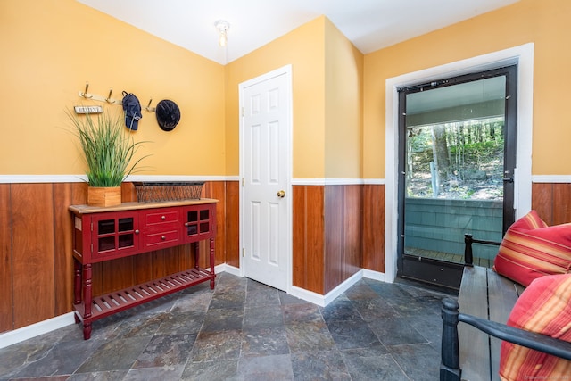 doorway to outside with wood walls