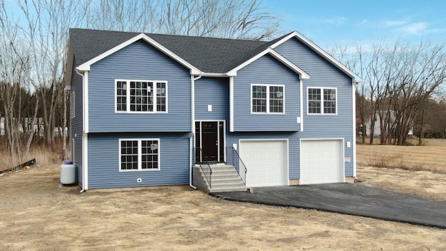 split foyer home featuring a garage, aphalt driveway, and roof with shingles