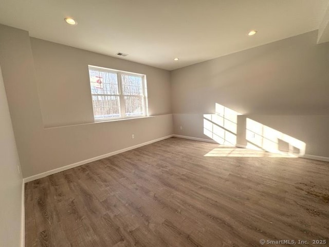 spare room with recessed lighting, wood finished floors, visible vents, and baseboards