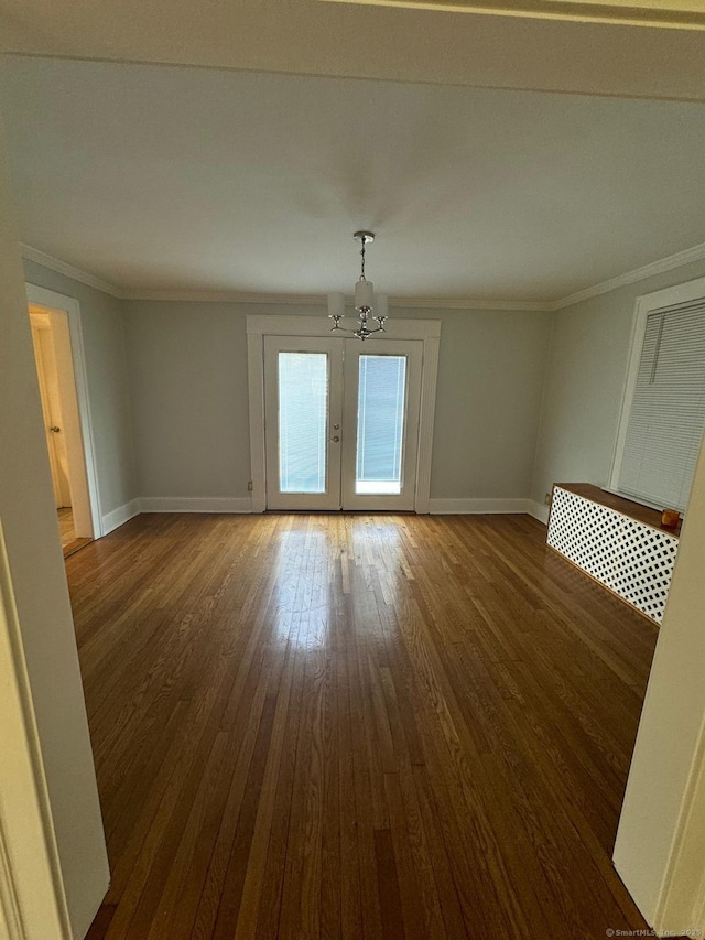 unfurnished room featuring french doors, dark hardwood / wood-style floors, crown molding, and a notable chandelier